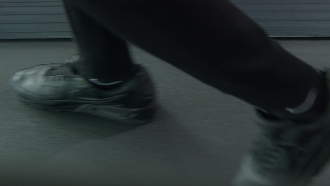 an athlete walking on treadmill Side angeled shot with an equipment placed at the forground, Close up shot