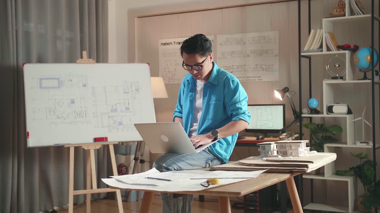 Asian Man Engineer Sitting On The Table And Using A Laptop To Work At The Office