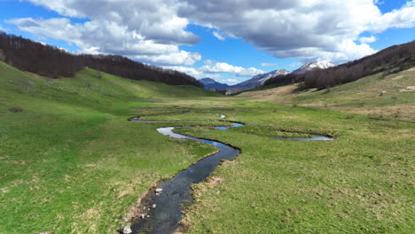 flight over a winding mountain stream with clear water on a sunny spring day