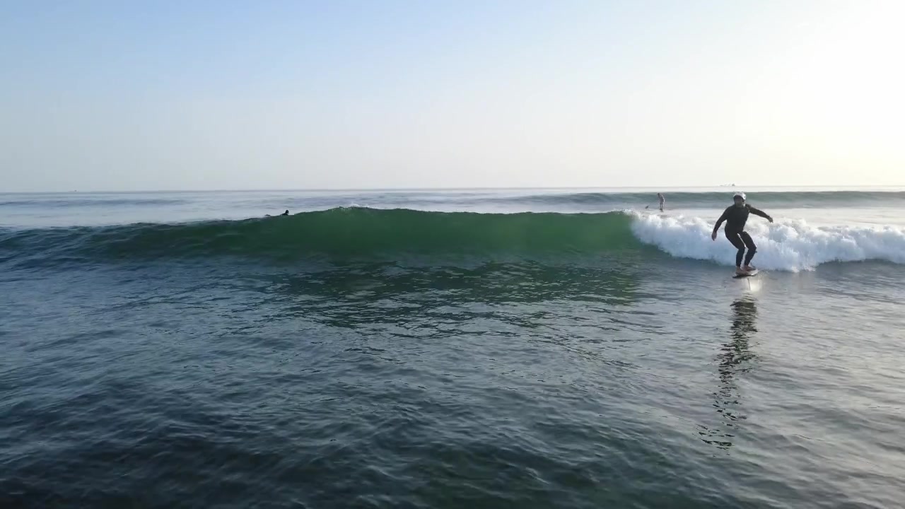 Rider di foil in posizione prona sull'oceano, in attesa di prendere l'onda perfetta ed eseguire un potente decollo con equilibrio, velocità e controllo.