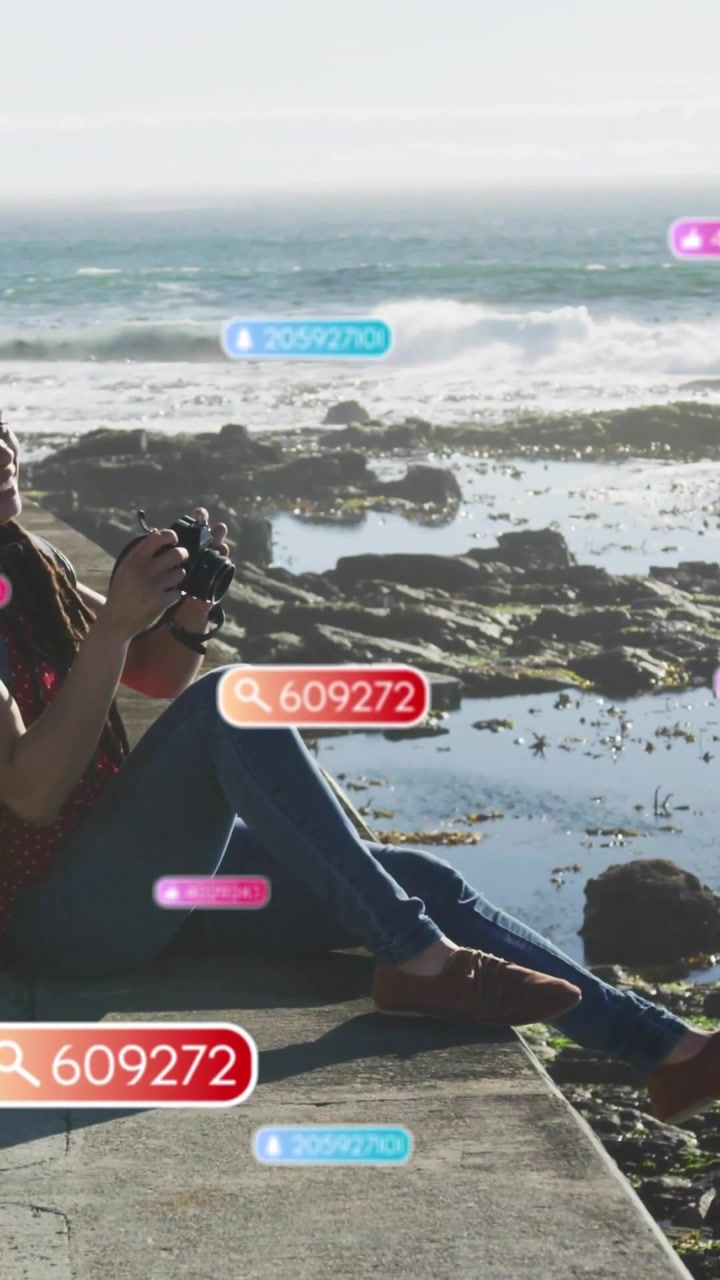 Vertical video: Woman shooting on ledge pressing shutter causing badges fading and revealing coast