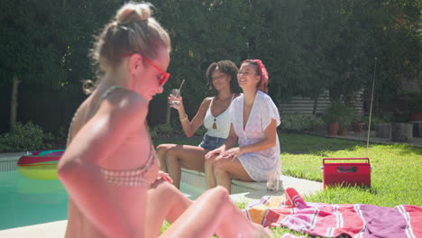 woman applying sunscreen by pool while friends laugh and enjoy drinks nearby
