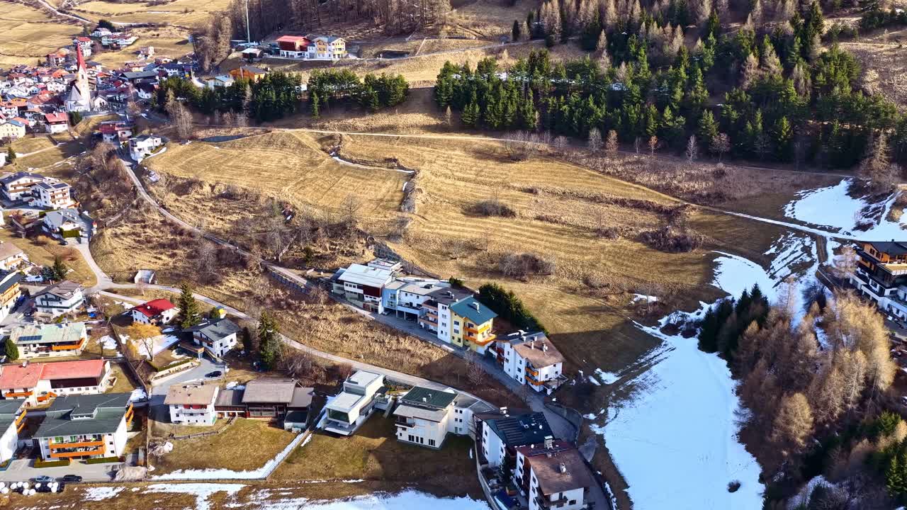 Panorama z drona europejskiego miasteczka górskiego z płatami śniegu, lasem i iglicą kościoła – Nauders, Austria.