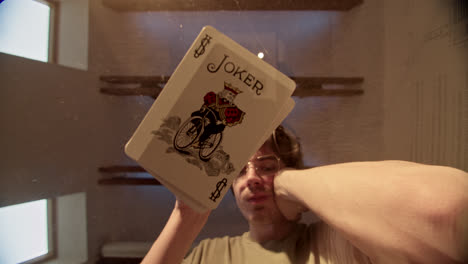 close-up of a joker playing card held by a person