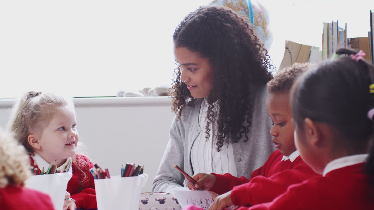 una maestra de escuela infantil sonriente en una mesa en una clase de arte, de cerca, retroiluminada