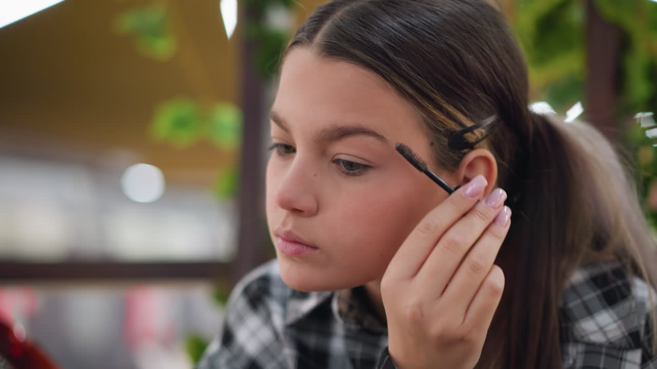 vista de primer plano de una dama usando un pincel de cejas para tallar y dar forma a las cejas con precisión, centrarse en el proceso de aseo detallado, con un fondo borroso que muestra un entorno de belleza relajado