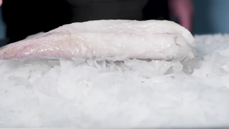 frozen fish meat falls into crushed ice bed on public market