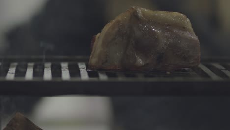 A-thick-cut-of-pork-placed-on-a-wood-flame-grill-to-roast---isolated-slow-motion