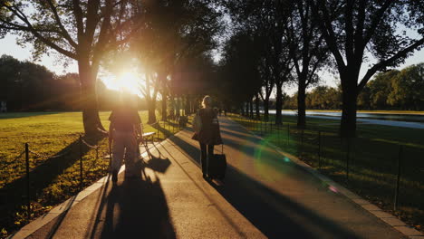 woman with suitcase in park at sunset