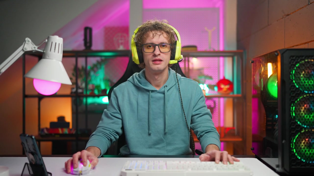 Giovane uomo con cuffie da gaming che guarda la telecamera in una stanza al neon