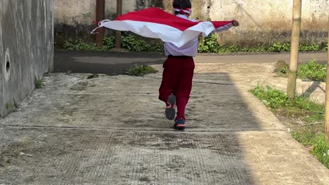 vista trasera de un estudiante de primaria corriendo y agitando la bandera indonesia celebrando el día de la independencia