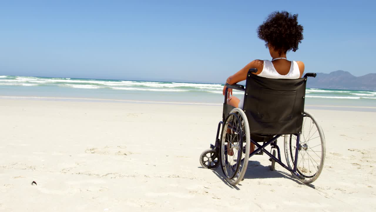 Disabled woman sitting on wheelchair at beach 4k