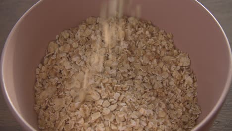 oat flakes being poured in pink bowl morning breakfast food