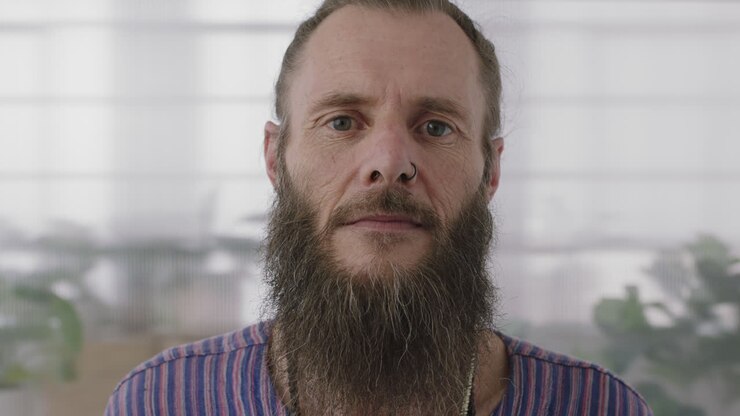 ritratto ravvicinato di un imprenditore hippie maturo uomo che guarda seriamente alla telecamera fiducioso imprenditore con barba funky