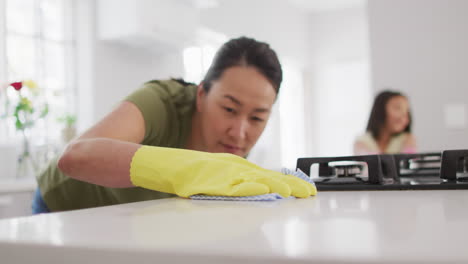 video of happy asian mother and daughter cleaning kitchen