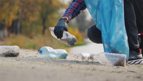 a man in gloves picks up plastic trash on the beach puts it in a bag garbage collection and environm