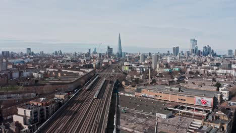 aerial drone shot of trains entering central london bridge station shard