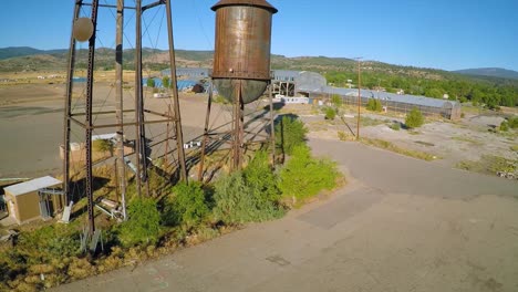 An-aerial-rising-shot-over-an-abandoned-factory-mill-and-water-towers-in-Northern-California