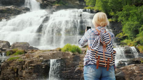 uma jovem fotografa uma pitoresca cachoeira tvindefossen na noruega - uma viagem à escandinávia e