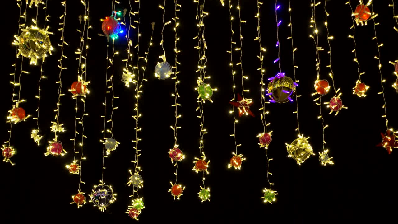 크리스마스 또는 새해의 다채로운 장식은 밤 하늘을 향해 바람에 흔들립니다.