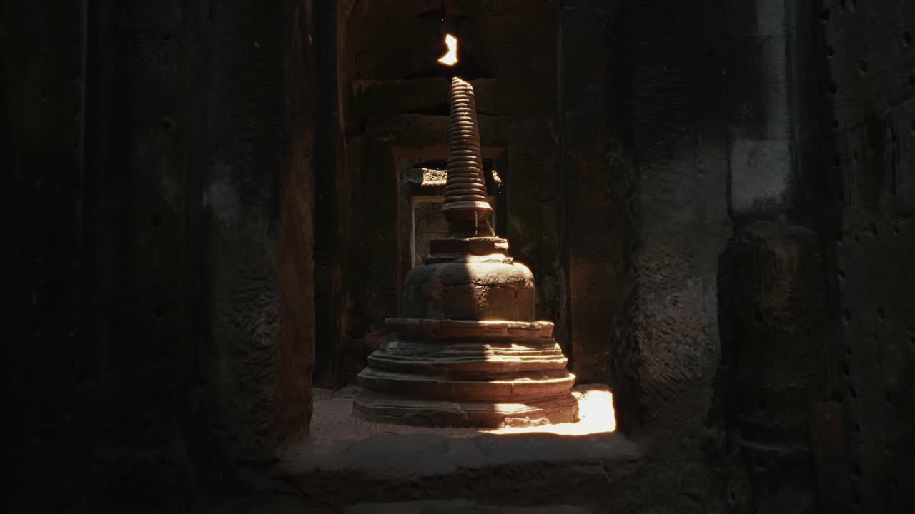 Vista interna dell'antico altare lingam in pietra illuminato dalla luce all'interno del corridoio di un tempio oscuro ad Angkor Wat, in Cambogia, che mostra il simbolismo sacro, la storia e il patrimonio