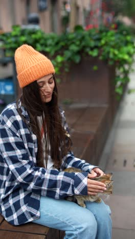 woman petting a cat on a city bench