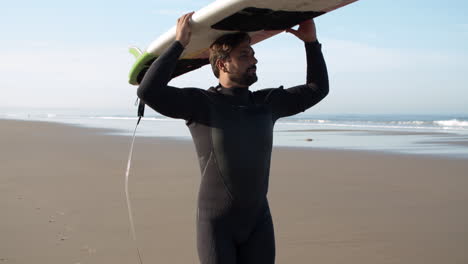 vertical motion of a male surfer with prosthetic leg walking on beach with surfboard on his head