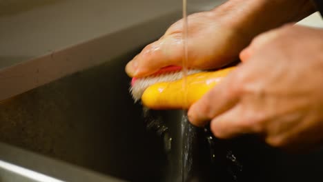 cleaning of carrot using water and by rubbing through brush on basin.