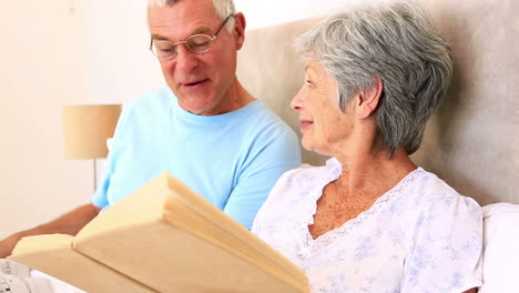 Happy-senior-couple-sitting-in-bed-reading