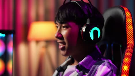 close up of excited asian teen boy gamer celebrates victory while playing video game on computer