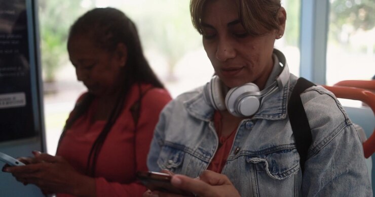 Two Women Using Smartphones While Riding Public Transportation