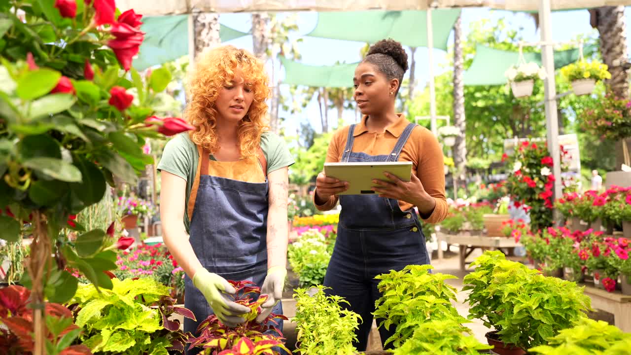 Two women working in a garden center with flowers and plants