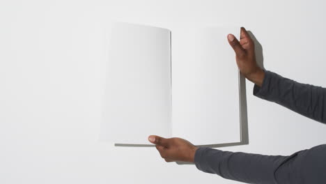 video of hand of african american man holding book with blank pages, copy space on white background