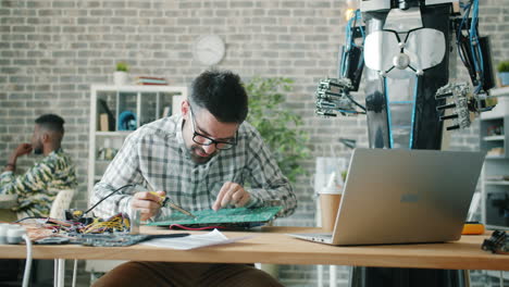 engineer working on a circuit board near a robot