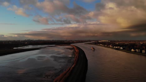 cargo ship sailing at noord river passing by natuureiland sophiapolder in hendrik-ido-ambacht, netherlands at sunset