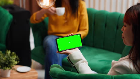 Asian-woman-holding-phone-with-isolated-greenscreen-in-lobby