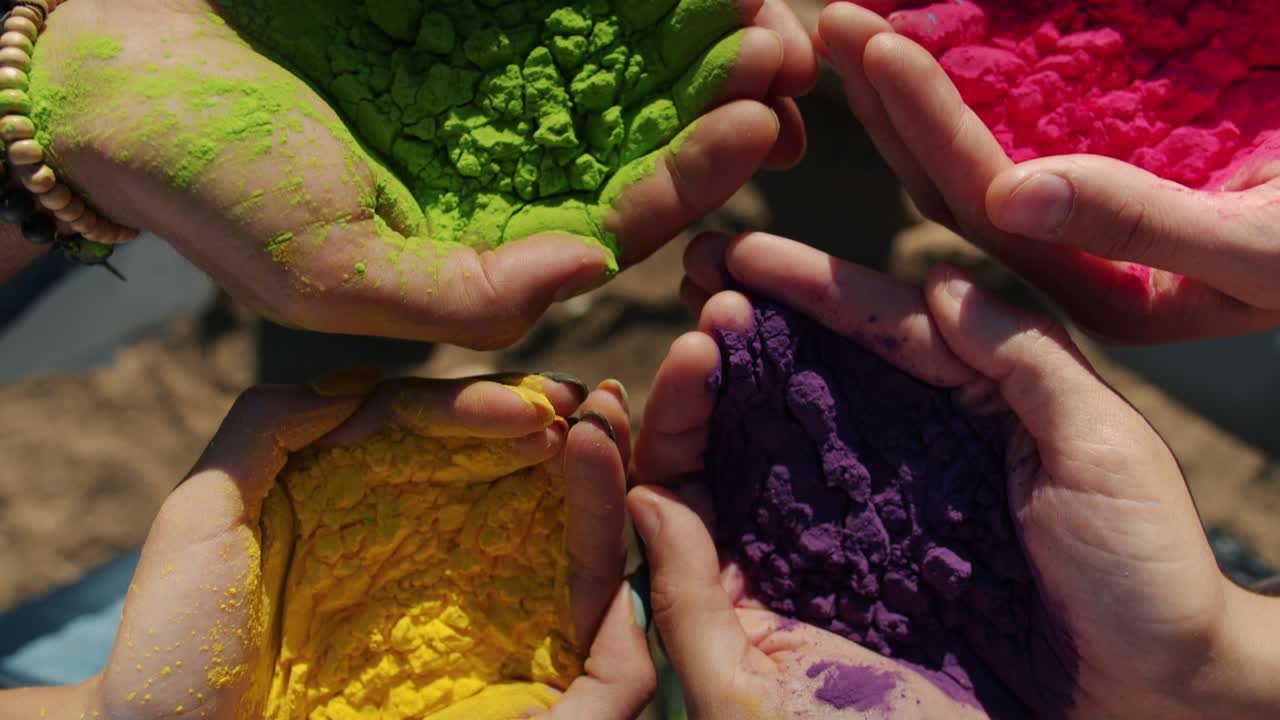 Primo piano di mani maschili e femminili che tengono polvere colorata durante il festival Holi