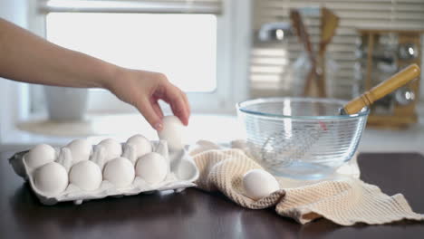 panadero tomando huevos de la caja de cartón y poniéndolos en la mesa de la cocina. huevos de pollo frescos