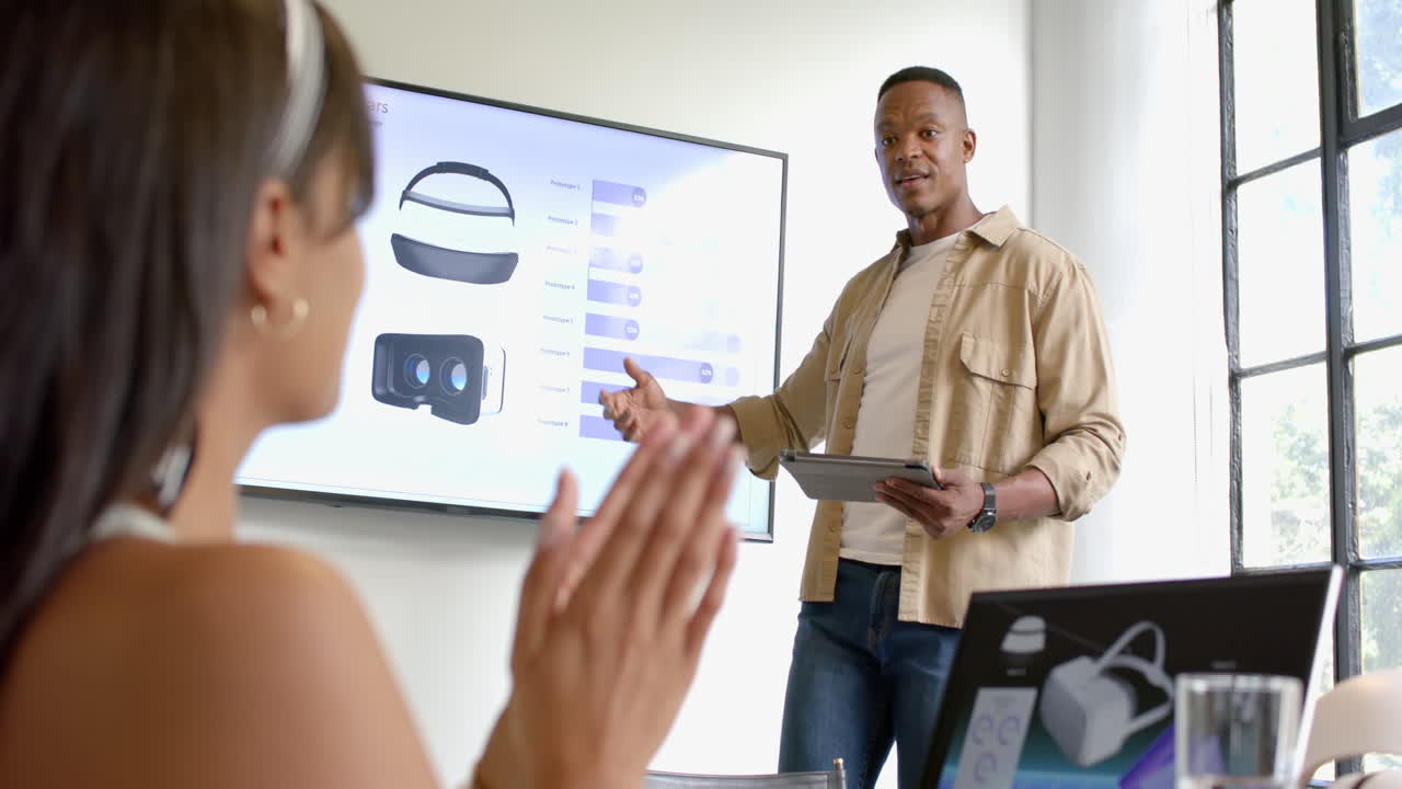 Presenting VR headset features, African American man using tablet and screen in business meeting