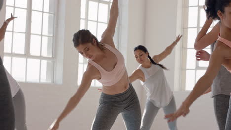 yoga class instructor teaching triangle pose to beautiful group of women enjoying healthy lifestyle exercising in fitness studio meditation