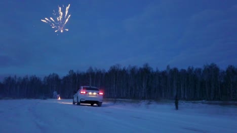 coche blanco en una carretera nevada con fuegos artificiales por la noche