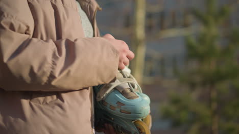 close-up of a girl walking through a park on a sunny day, wearing a peach jacket and a grey inner shirt. she is holding a skateboard, with her eyes closed, enjoying the warmth of the sun on her face