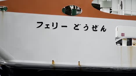 japanese car ferry moving through left of frame with ramp down