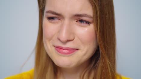 mujer llorando sonriendo a la cámara en fondo gris en el estudio. triste y feliz