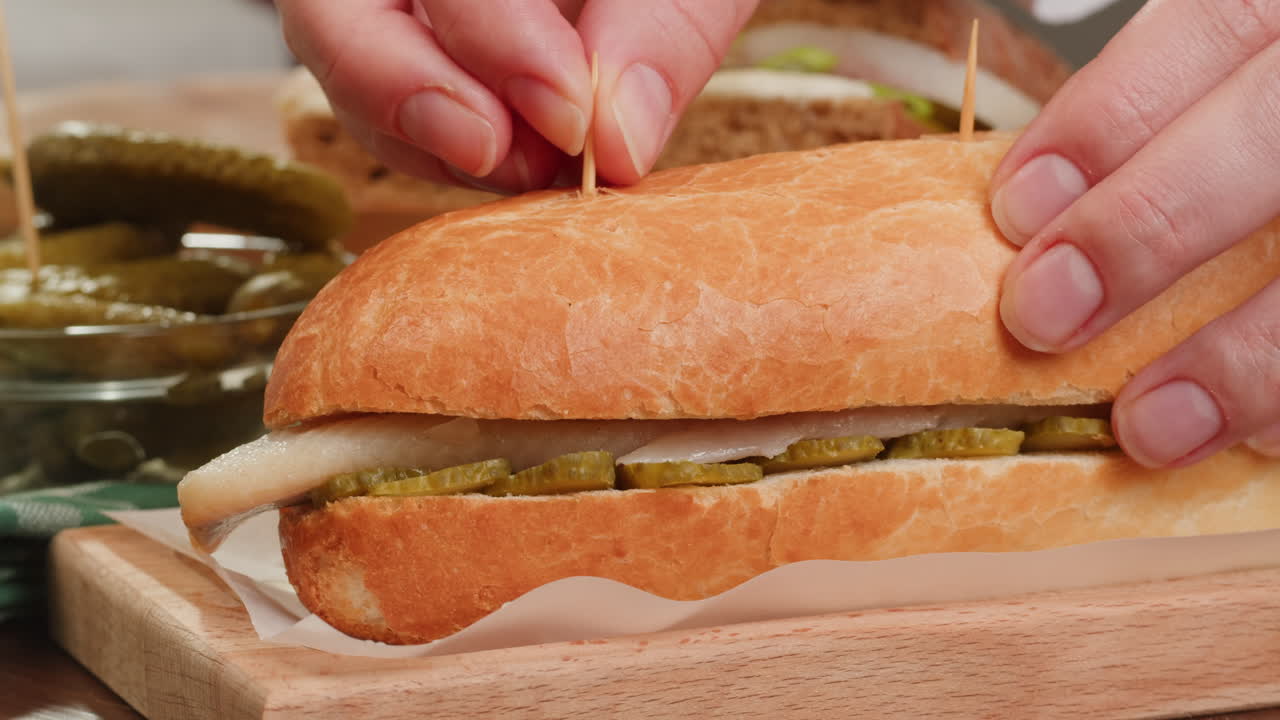 Preparing a herring sandwich with pickles
