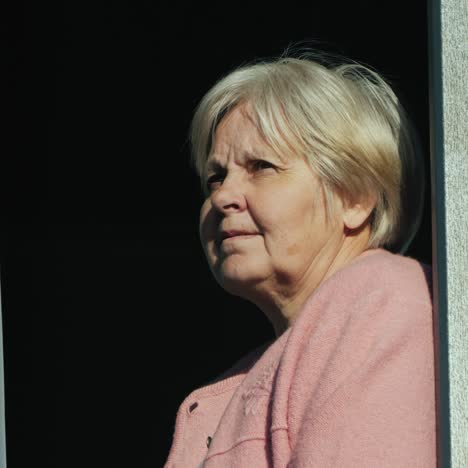 Portrait-Of-An-Elderly-Woman-Looking-Out-Of-The-Window-Of-Her-Home