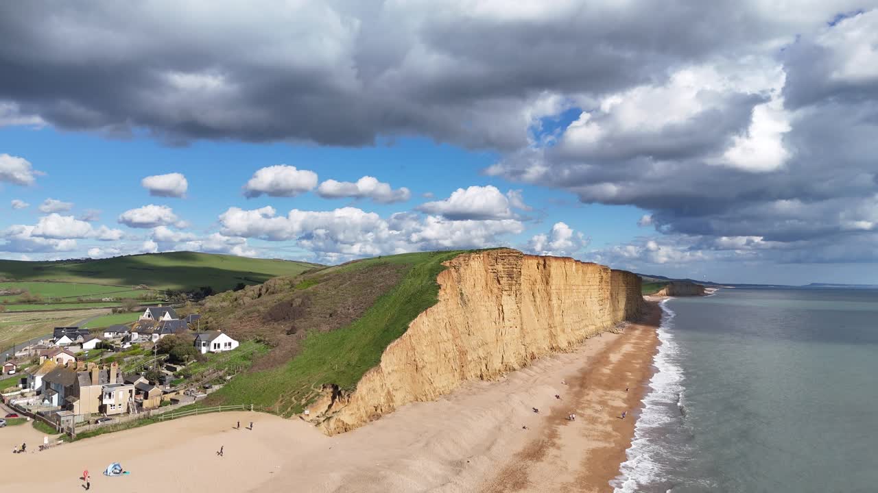 Spiaggia di West Bay, Dorset, enormi scogliere di arenaria, ripresa con drone in avvicinamento 4K.
