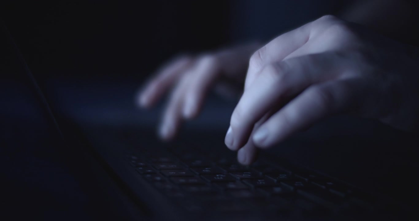 Mani che scrivono sul portatile di notte