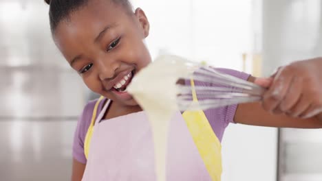 Feliz-Chica-Afroamericana-Inalterada-Divirtiéndose-Horneando-Pastelitos-En-La-Cocina,-En-Cámara-Lenta