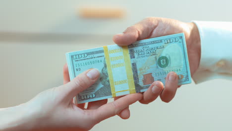 a caucasian woman handing a latino male a stack of cash